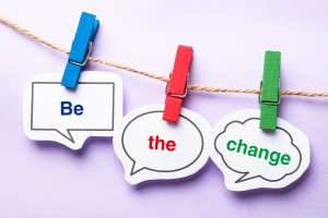 Be the change paper bubbles with clip hanging on the line against purple background.
