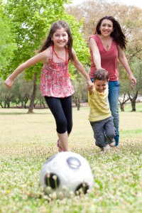 Childrens playing soccer with their mother